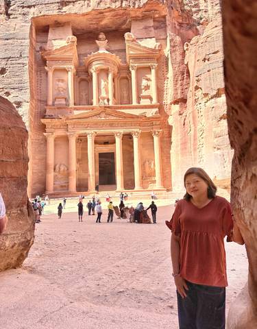 Woman standing in front of the iconic Treasury facade in Petra.