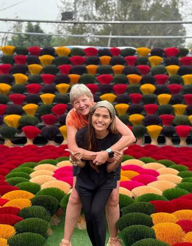Two people posing in front of colorful incense sticks.