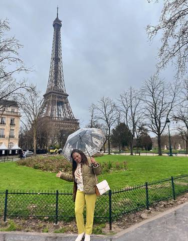 Person holding an umbrella in front of the Eiffel Tower.
