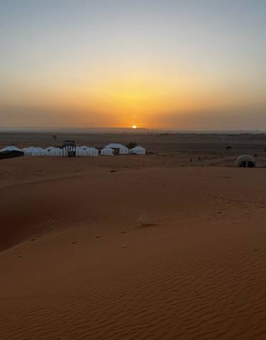 Desert tents with sunset in the background.