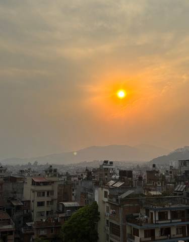 A city skyline with a sunset sky and mountain silhouette.