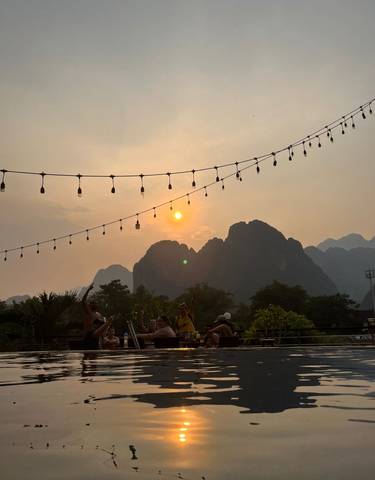 People enjoying sunset at a rooftop with mountain backdrop.
