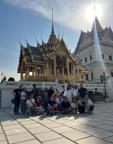 Large group posing in front of a golden temple.
