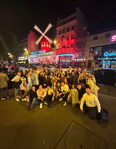 A large group of people outside the Moulin Rouge at night.