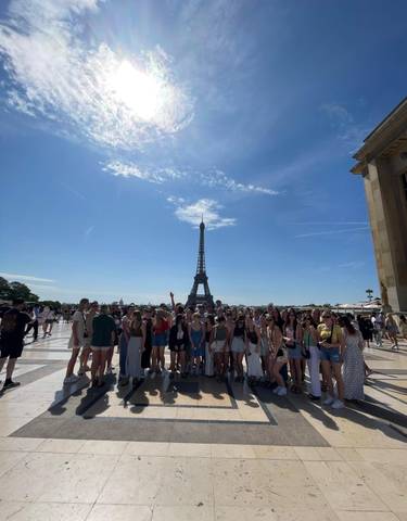 Group photo in front of the Eiffel Tower under a sunny sky.