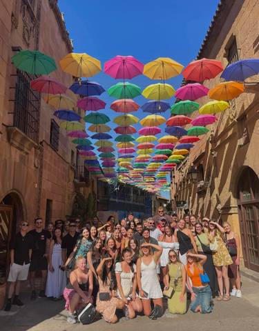 Group photo under a colorful canopy of umbrellas.