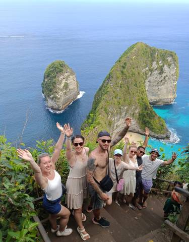People posing with high cliffs and turquoise waters in the background.