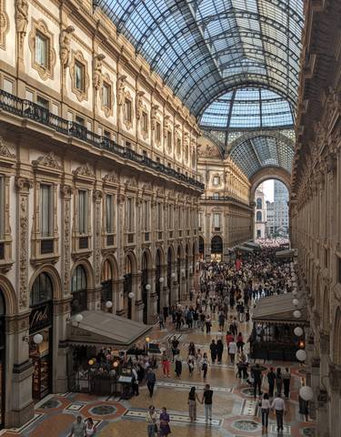 A bustling interior of a grand shopping gallery with a glass ceiling.