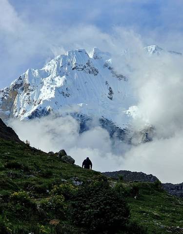 Person hiking near a snow-capped mountain.