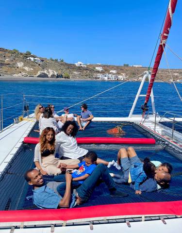 People relaxing on the deck of a boat with coastal view.