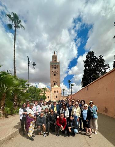 Group of people posing in front of a tall minaret in a historical setting.