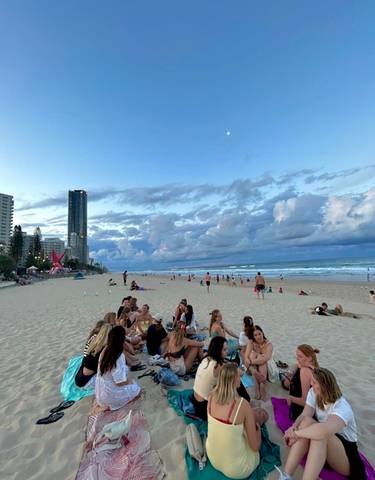 Beach scene with people relaxing and buildings in the background.