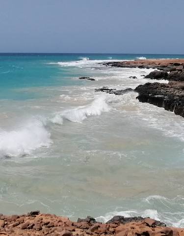Waves crashing against rocky shorelines with a vibrant sea.