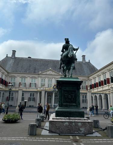 Statue of a rider on horseback in front of a grand building.