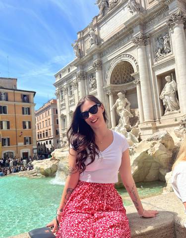 Person posing in front of a famous fountain.