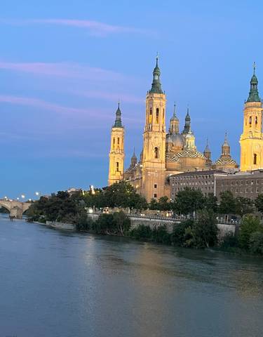 Illuminated basilica by the river in the evening.