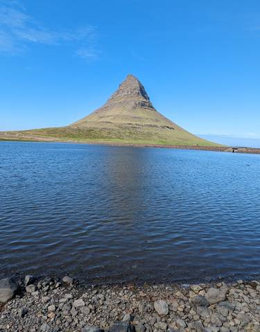 Mountain with a distinct pointed shape reflected on a lake.