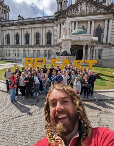Large group of people posing in front of the Belfast sign.