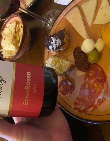 Wine and assorted meats and cheeses on a plate.