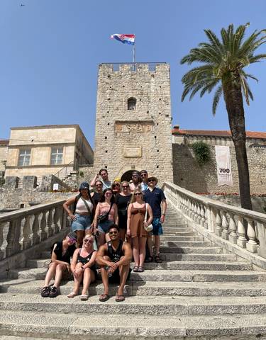 Group of people on stairs with a historic stone tower.