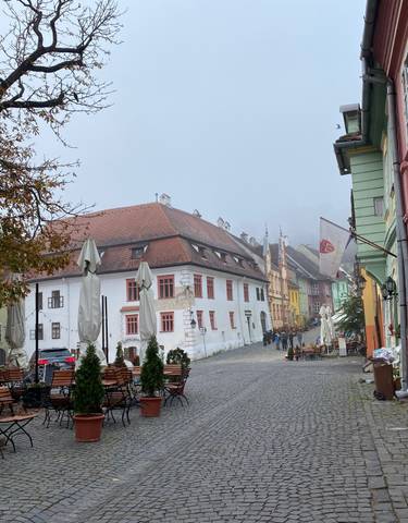 Cobbled street with colorful buildings and outdoor seating.