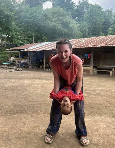 Woman playing with a child in a rustic village setting.