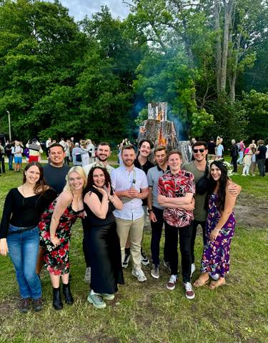 Festive group gathering outdoors with large bonfire.
