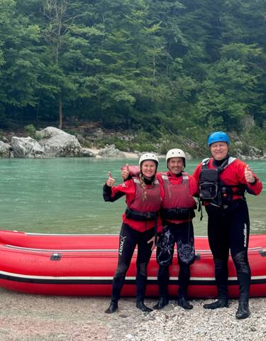 Three people posing with thumbs up by a red raft.