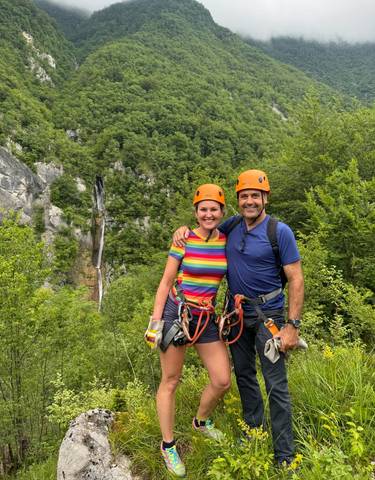 Two people in climbing gear with a waterfall in the background.