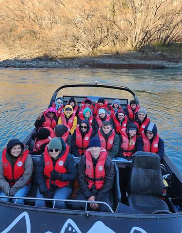 A group of people in a boat wearing life jackets.