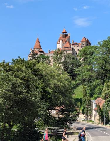 Bran Castle surrounded by green trees.