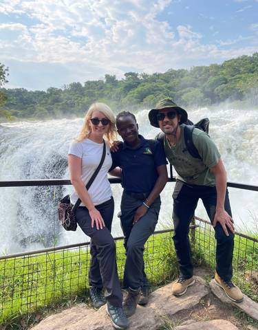 Three people posing in front of a large waterfall.