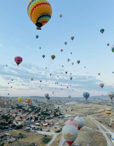 Hot air balloons filling the sky over a valley.