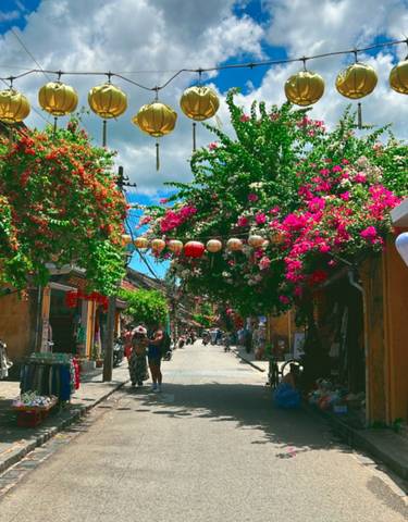 Colorful street market with hanging lanterns and flowers.