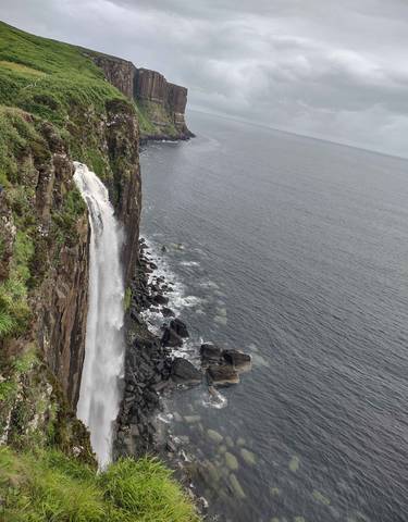 A dramatic waterfall cascading down a cliff into the sea.