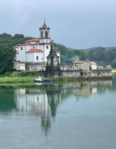Historic church with a clock tower reflected in water.