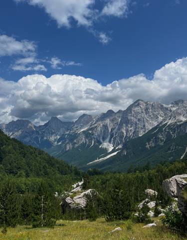 Majestic mountain range with forested valleys and dramatic clouds.