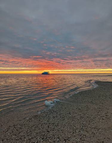 A beautiful sunset over the ocean with a boat in the distance.