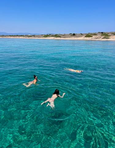 Three people swimming in clear blue water.