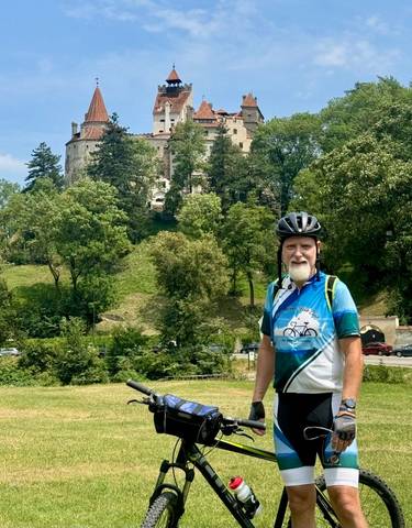 Cyclist with Bran Castle in the background.