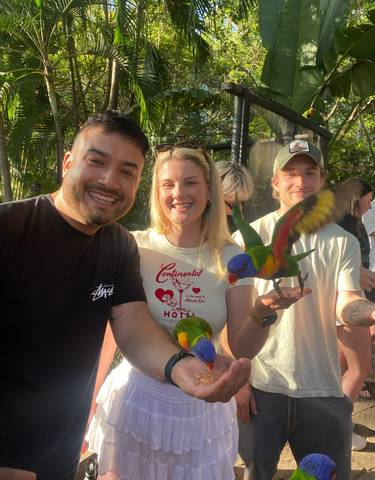 People interacting with colorful birds in a natural setting.