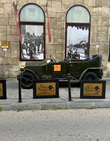 Historic car in front of a museum with war photos.