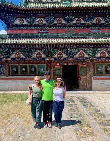 Three people posing in front of a decorated building.