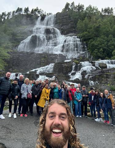A large group of people in front of a waterfall.