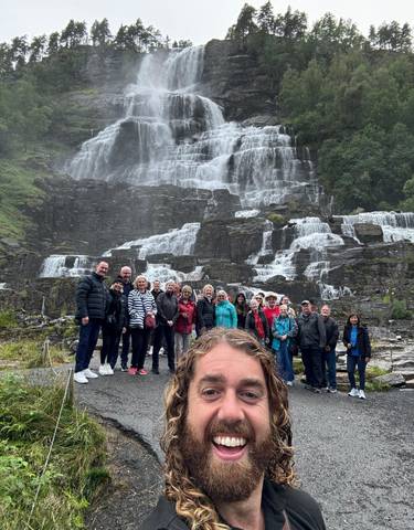 A group standing in front of a multi-tiered waterfall.