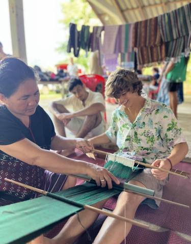A local woman guiding a tourist in a traditional weaving activity.