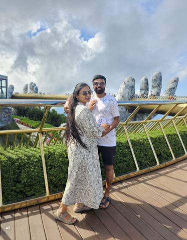 Couple posing on a bridge with mountainous background.