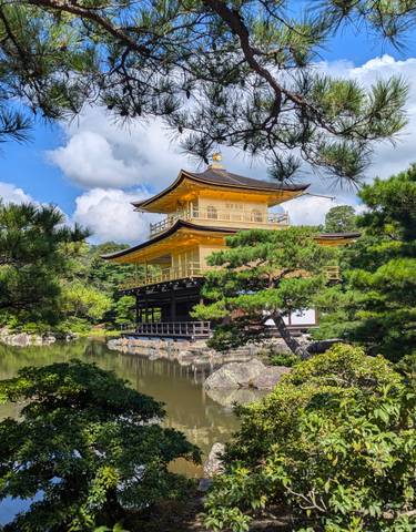 Golden pavilion surrounded by a garden and pond.