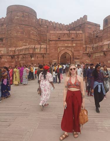 People walking in front of a red fort-like structure.