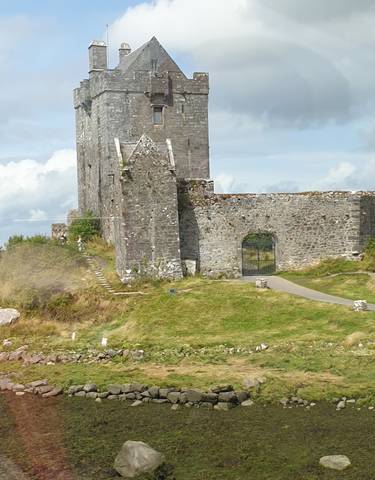 Stone castle ruins surrounded by green fields.
